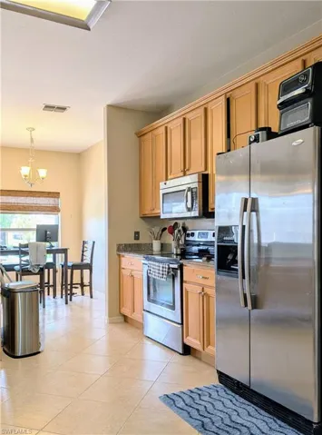 Eat in kitchen with tile floors, stainless steel appliances, decorative light fixtures