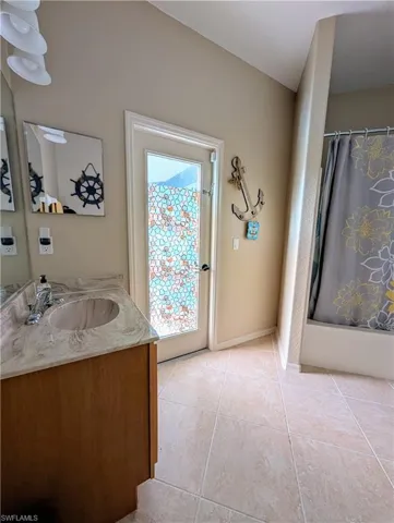 Extra bathroom with vanity, tile floors, and shower / tub combo, opens to pool.