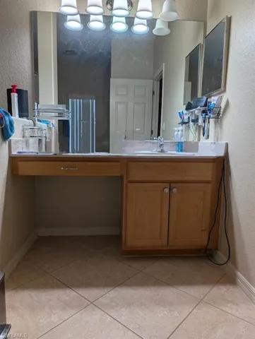 Bathroom featuring a textured wall, tile patterned flooring, vanity, and baseboards