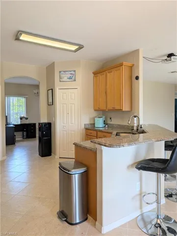 Kitchen featuring sink, tile floors, a breakfast bar, granite countertops.