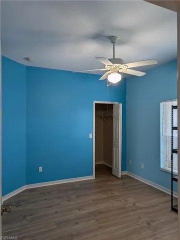 Bedroom, wood-type flooring, walk in closet, and ceiling fan.
