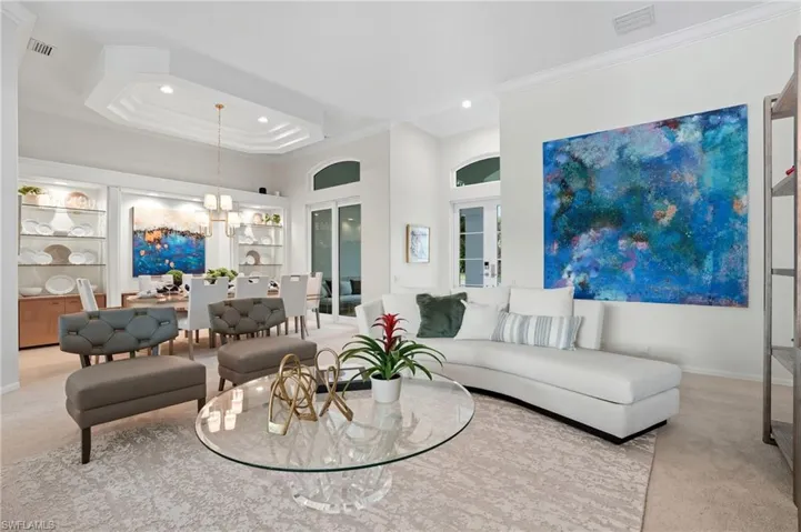 Living area featuring carpet flooring, crown molding, a chandelier, a raised ceiling, and recessed lighting