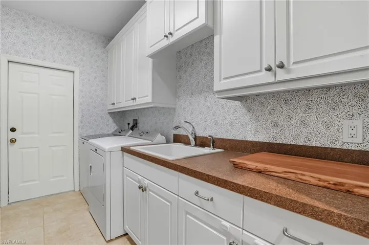 Washroom featuring cabinet space, light tile patterned floors, and washer and clothes dryer