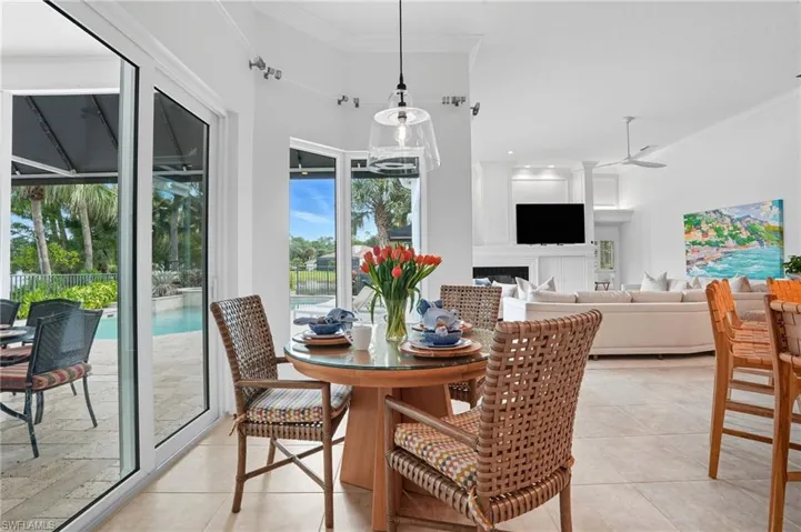 Dining area with crown molding, a fireplace, ceiling fan, and light tile patterned floors