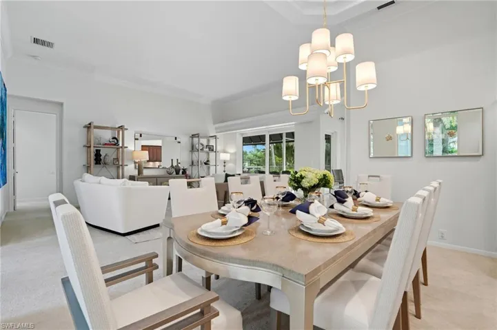 Dining room featuring light colored carpet, crown molding, and a chandelier