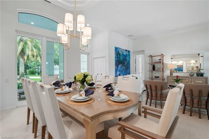 Dining space with light carpet, crown molding, and a chandelier