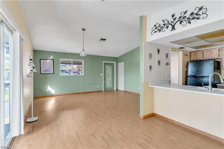 Kitchen with light countertops, freestanding refrigerator, light wood-style floors, pendant lighting, and a peninsula