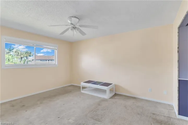 Spare room with a textured ceiling, carpet, and ceiling fan