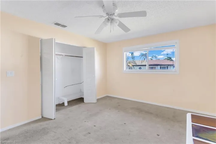Unfurnished bedroom featuring a textured ceiling, carpet floors, a ceiling fan, and a closet
