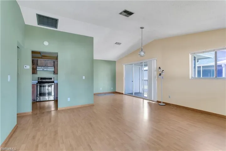 Unfurnished living room with vaulted ceiling and light wood-type flooring