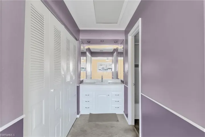 Hallway with light colored carpet and a sink