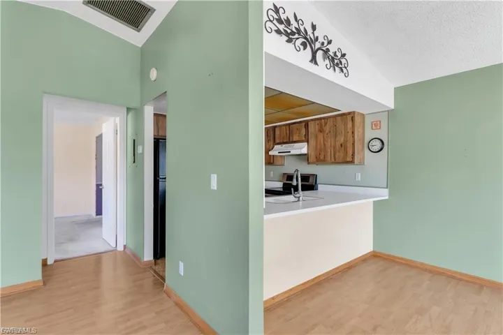 Kitchen featuring light countertops, light wood finished floors, electric stove, wood finish cabinets, and freestanding refrigerator