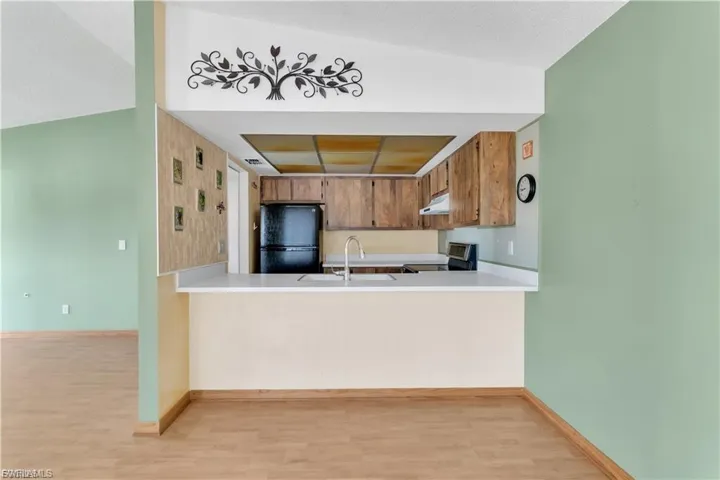 Kitchen featuring light countertops, light wood finished floors, freestanding refrigerator, stainless steel range, and wood finish cabinets