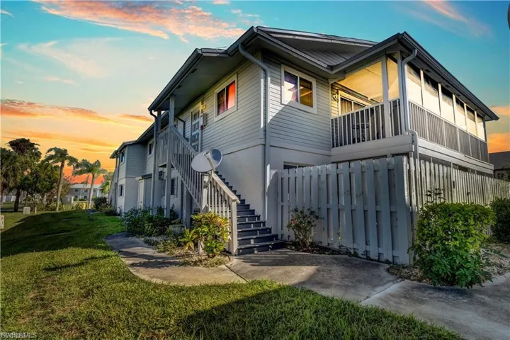 Property exterior at dusk featuring a lawn and a balcony