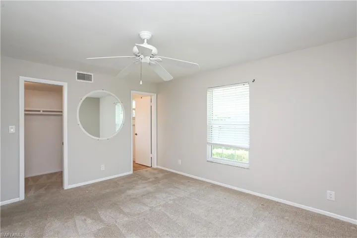 Unfurnished bedroom with a walk in closet, light colored carpet, ceiling fan, and a closet