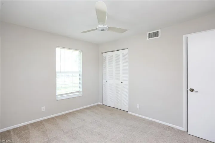 Unfurnished bedroom with ceiling fan, a closet, and light colored carpet