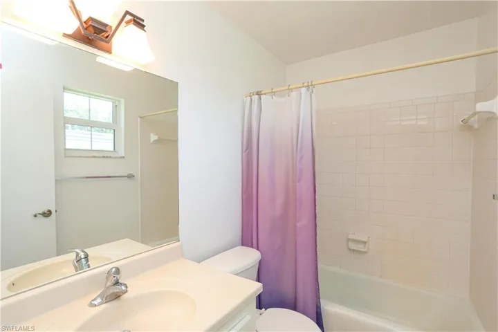 Full bathroom with toilet, shower / bath combo with shower curtain, and vanity