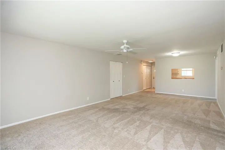 Empty room with ceiling fan and light colored carpet