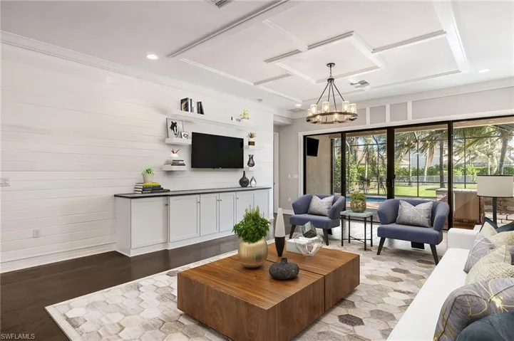 Massive great room with custom built-in, trim molding, and designer lighting (virtually staged)