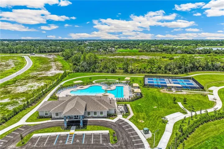 Community amenities featuring a clubhouse with paved parking, expansive swimming pool with lounge seating, and multiple sports courts