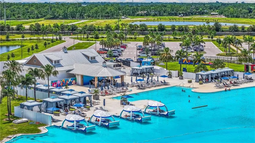 Expansive community recreation area featuring a large central building, multiple covered cabanas, a spacious swimming pool, and a recreational lagoon