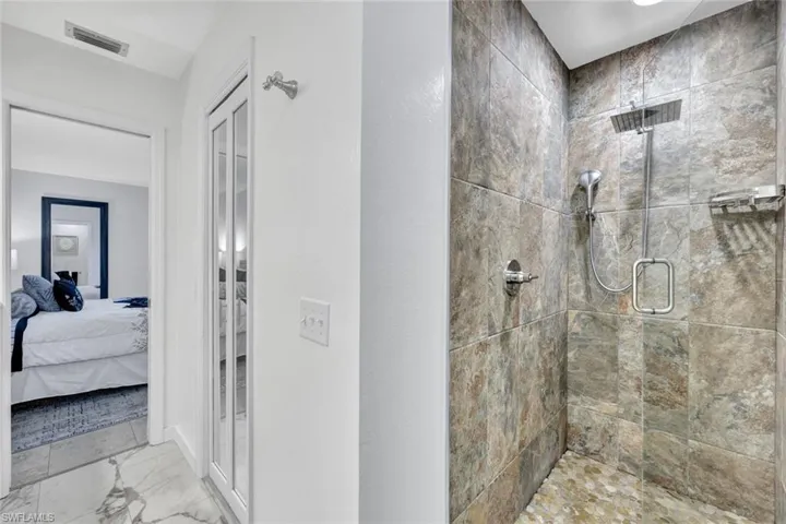 Ensuite bathroom featuring a stall shower and light marble finish floors