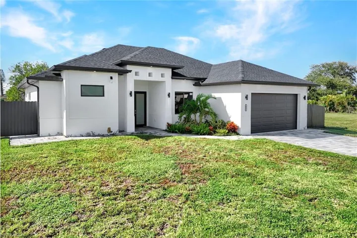 View of front of house featuring an attached garage, stucco siding, decorative driveway, and roof with shingles
