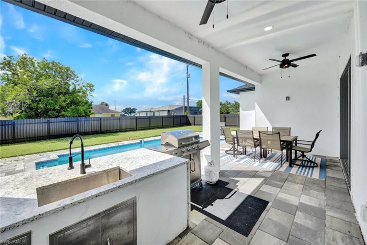 Fenced backyard with outdoor dining space, exterior kitchen, a patio, and a ceiling fan
