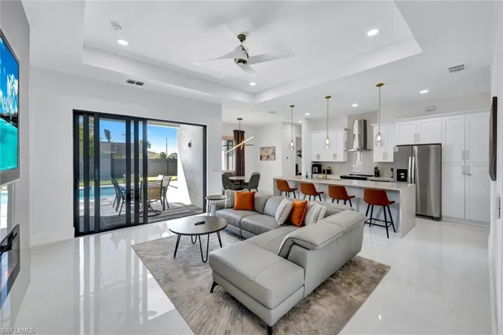 Living area with a raised ceiling, a ceiling fan, and recessed lighting
