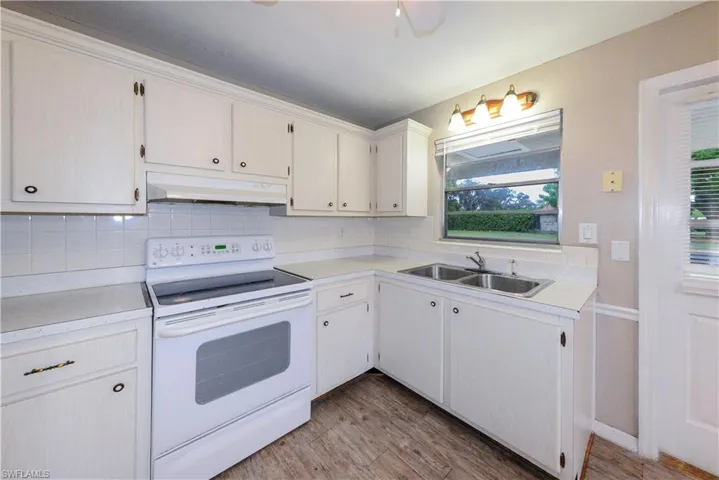 Kitchen featuring sink, white range with electric stovetop, hardwood / wood-style floors, and backsplash