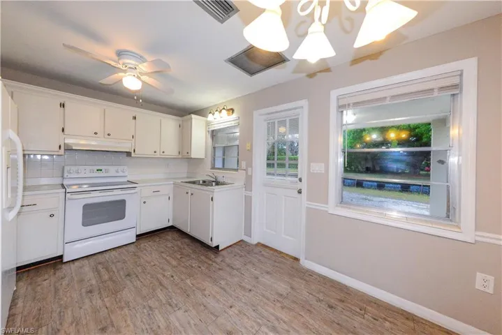 Kitchen with sink, backsplash, white cabinets, and white range with electric cooktop