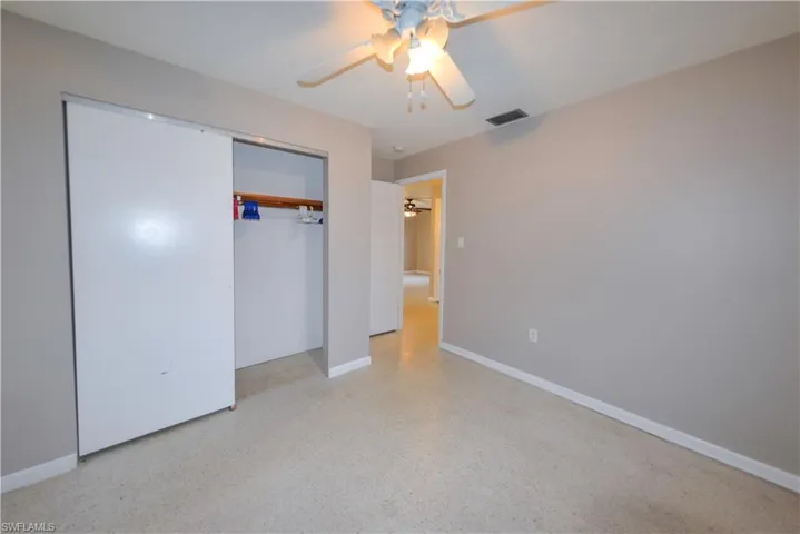 Unfurnished bedroom with ceiling fan and a closet