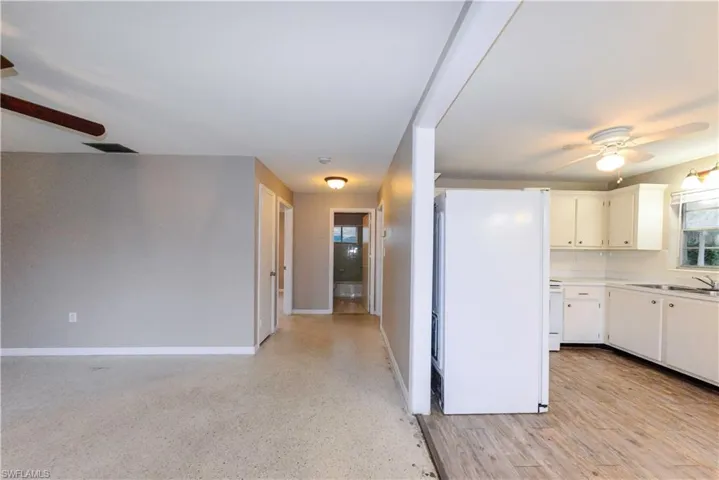 Kitchen with ceiling fan, sink, white refrigerator, white cabinets, and decorative backsplash