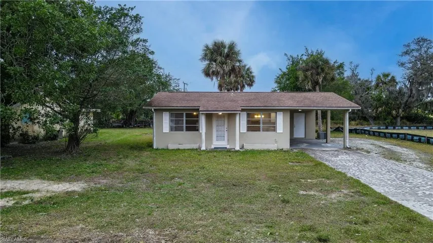 View of front of property with a carport and a front lawn