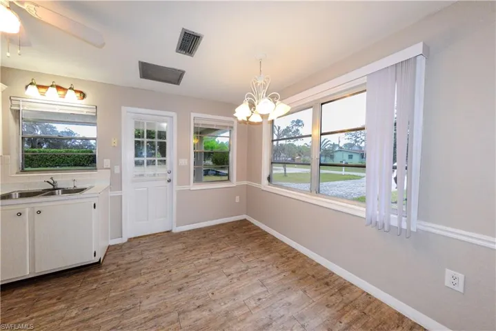Unfurnished dining area featuring sink, light hardwood / wood-style floors, and ceiling fan with notable chandelier