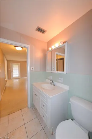 Bathroom featuring tile walls, tile patterned floors, vanity, and toilet