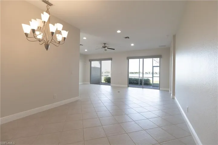 Unfurnished room featuring ceiling fan with notable chandelier and light tile patterned floors