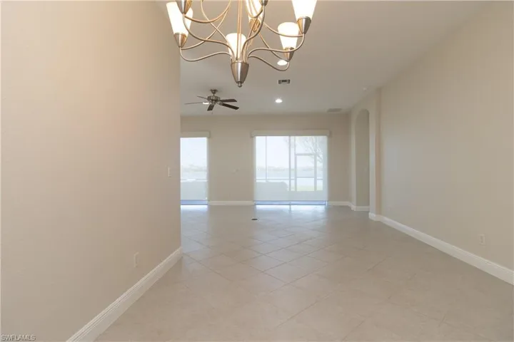Spare room with light tile patterned flooring and ceiling fan with notable chandelier