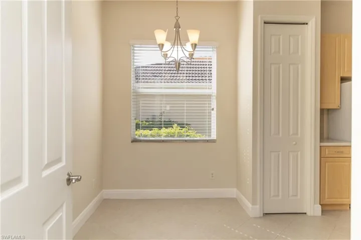 Unfurnished dining area with light tile patterned floors, an inviting chandelier, and plenty of natural light
