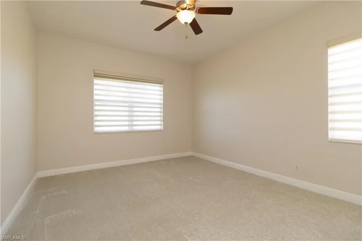Carpeted empty room with ceiling fan and a wealth of natural light