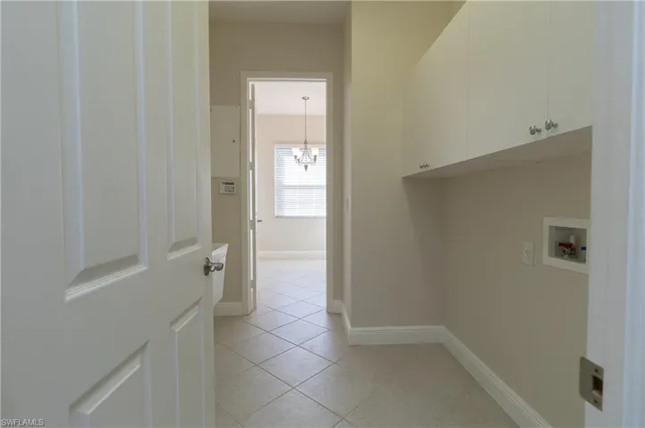 Washroom featuring cabinets, a chandelier, washer hookup, and light tile patterned floors