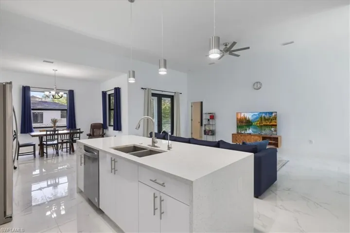 Kitchen featuring marble finish floor, open floor plan, appliances with stainless steel finishes, and a sink