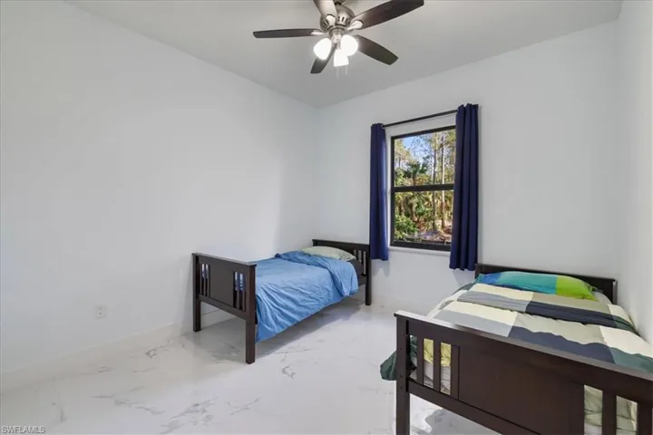 Bedroom with a ceiling fan, marble finish floor, and baseboards