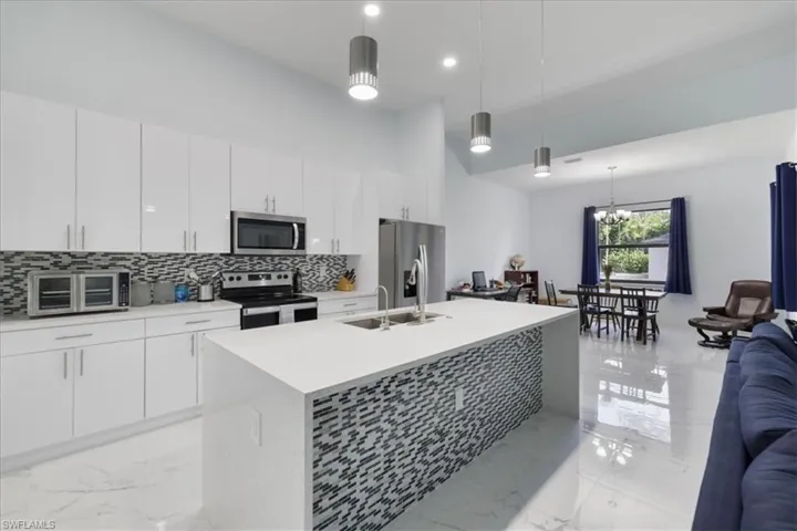 Kitchen featuring stainless steel appliances, marble finish floor, backsplash, a toaster, and open floor plan