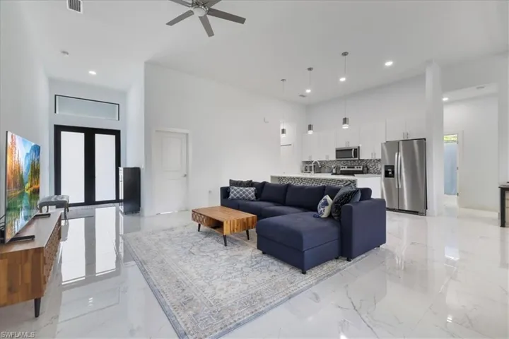 Living area with recessed lighting, a ceiling fan, a high ceiling, and marble finish floor