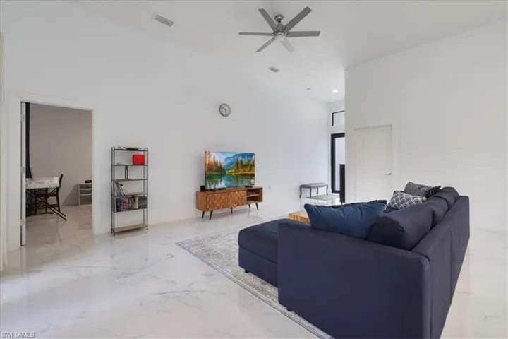 Living room featuring recessed lighting, a high ceiling, ceiling fan, marble finish floor, and visible vents