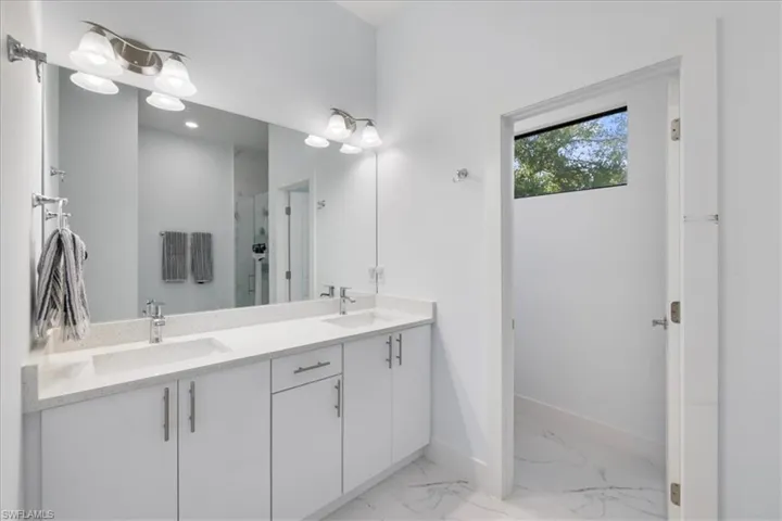 Bathroom featuring double vanity, baseboards, marble finish floor, and a sink