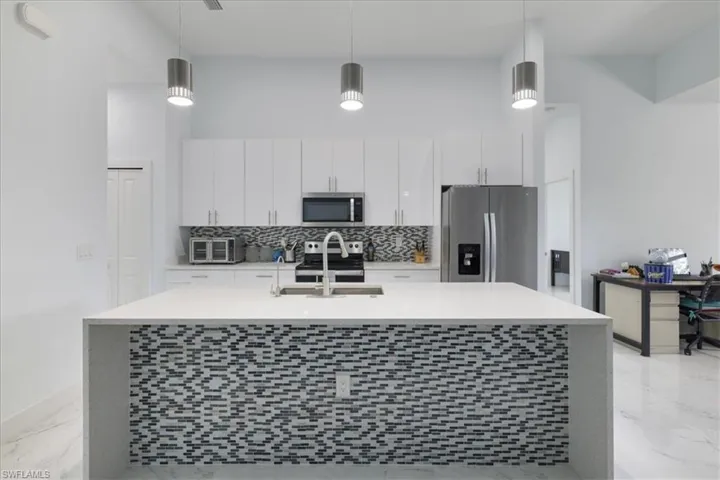 Kitchen with marble finish floor, appliances with stainless steel finishes, light countertops, and a sink