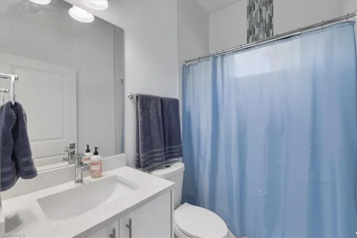 Bathroom with toilet, curtained shower, and vanity