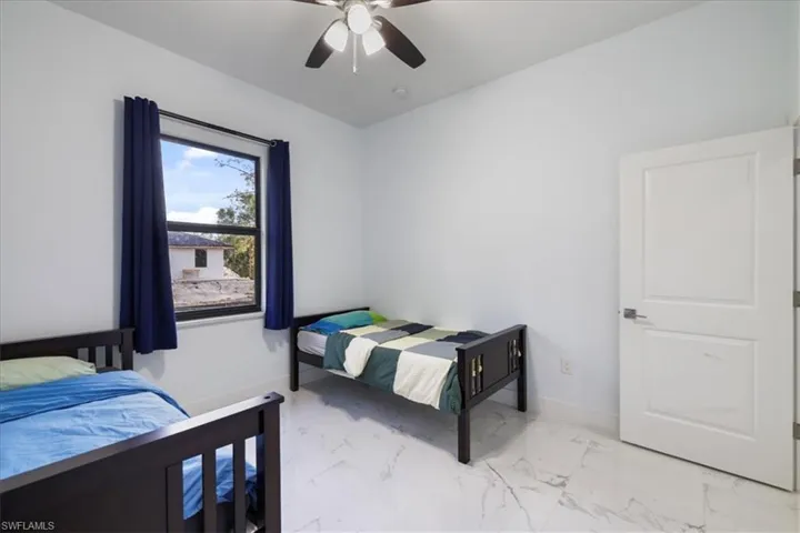 Bedroom with baseboards, a ceiling fan, and marble finish floor
